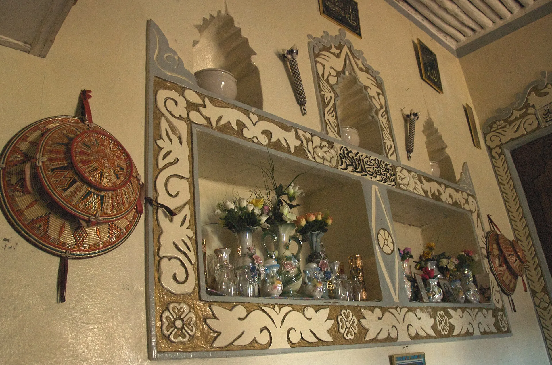Carved niches, baskets and enamel plates on the wall of a traditional Harari home